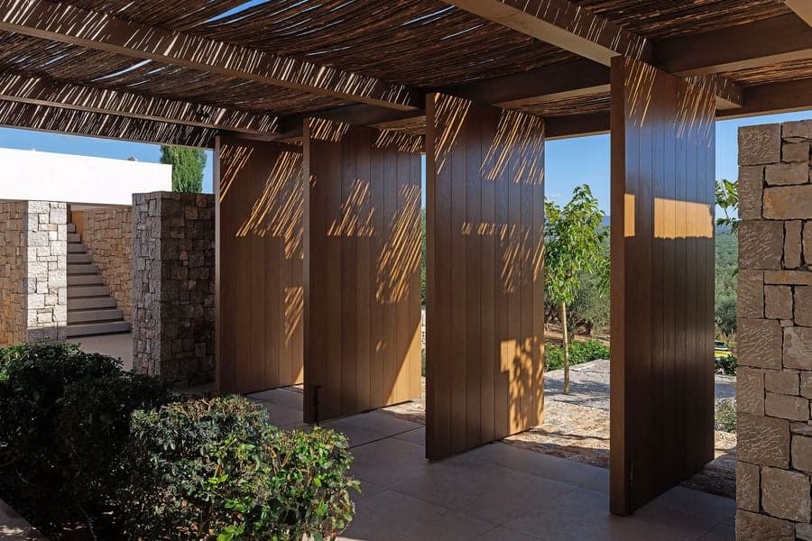 Outdoor dining space beneath woven pendant lights and timber pergola