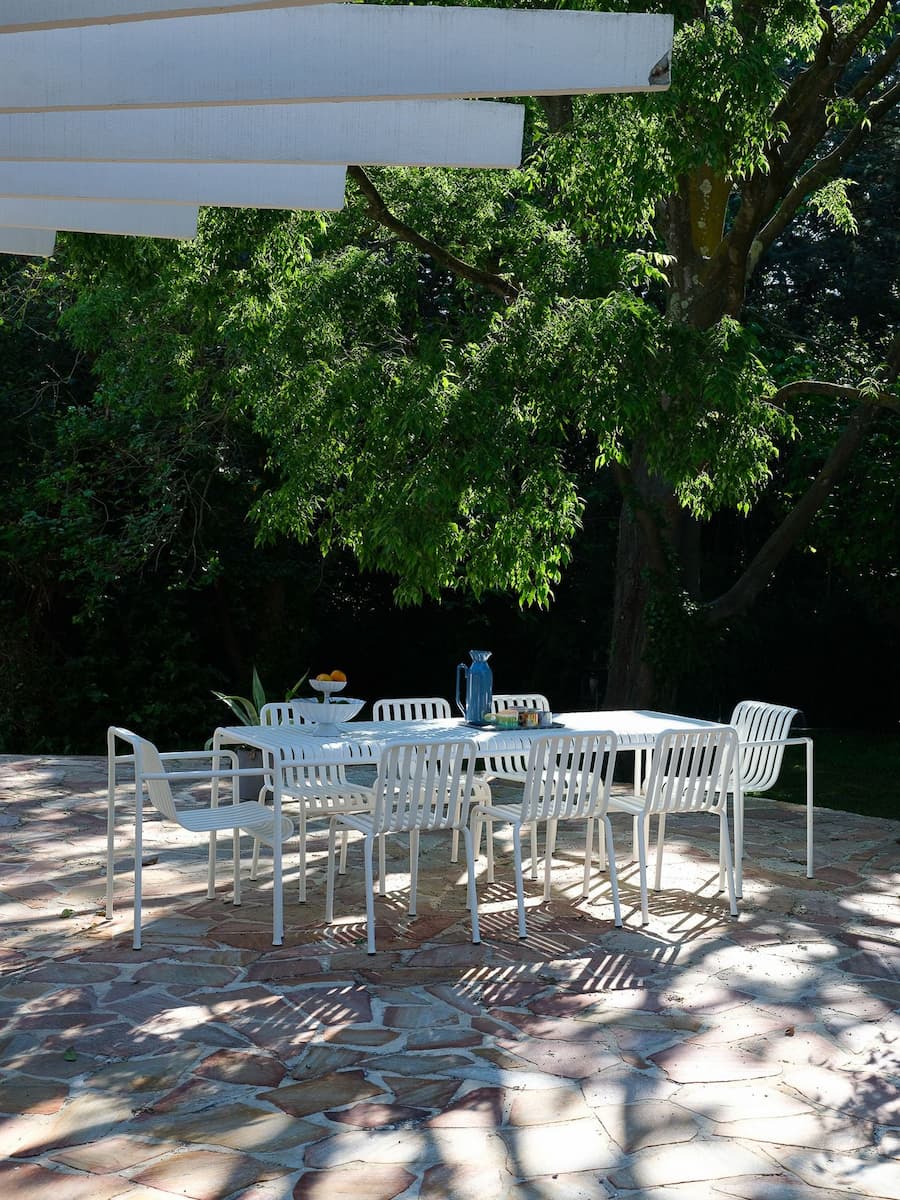 Outdoor dining terrace beneath a white pergola at Villa Bank surrounded by mature garden landscape
