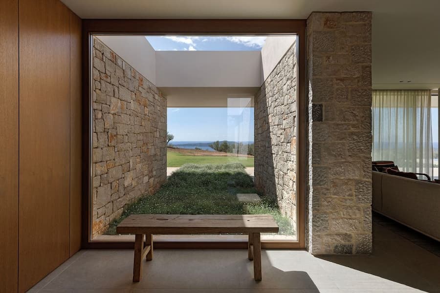 Picture window framing a stone courtyard and distant sea beyond the entrance