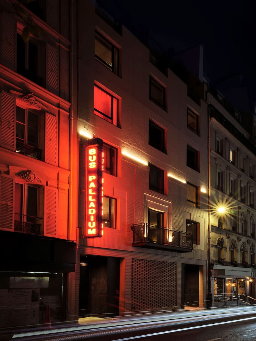 Bus Palladium Hotel Paris facade illuminated by its iconic red neon sign