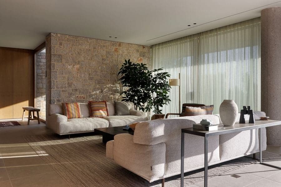 Living room combining local stone walls, soft textiles and filtered daylight