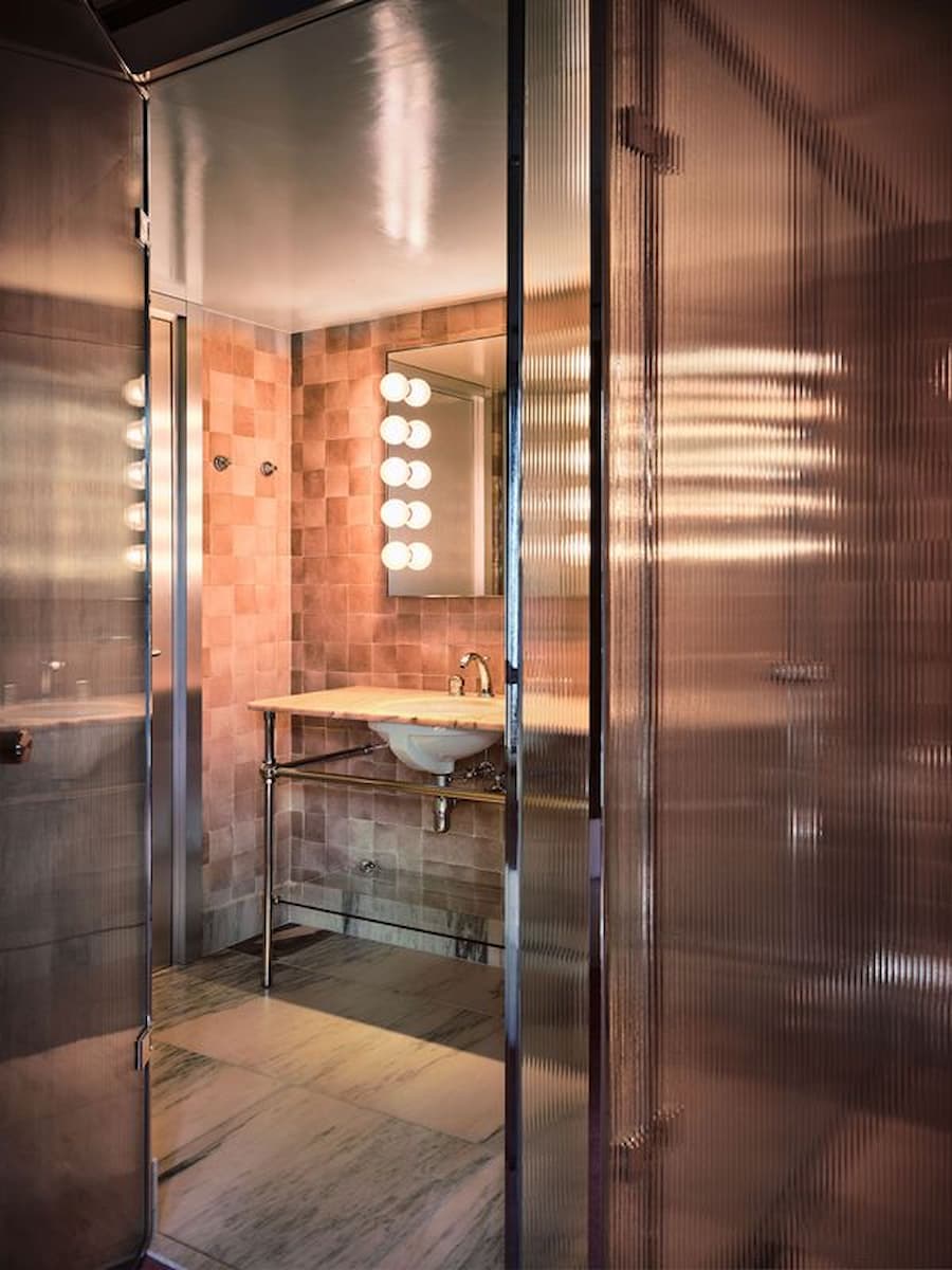 Ribbed glass bathroom with pink stone tiles inside Bus Palladium Hotel Paris by Studio KO