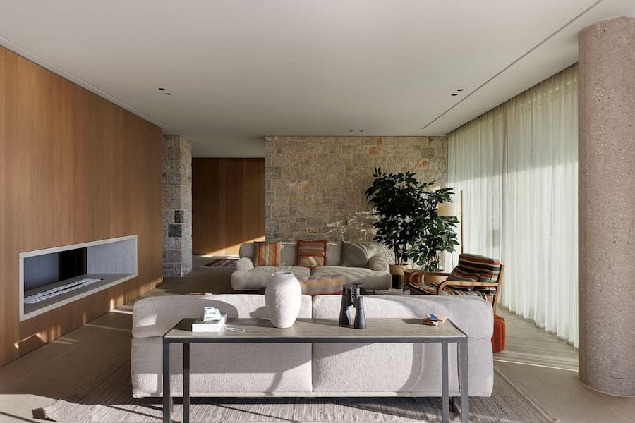 Minimalist living room centred around a linear fireplace and natural materials