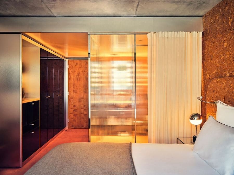 Suite bedroom with cork walls and translucent glass partitions at Bus Palladium Hotel Paris
