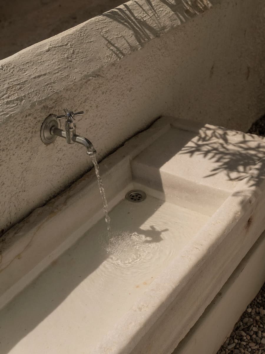 Traditional marble water basin integrated into the minimalist Cycladic courtyard at YAPA Antiparos in Greece