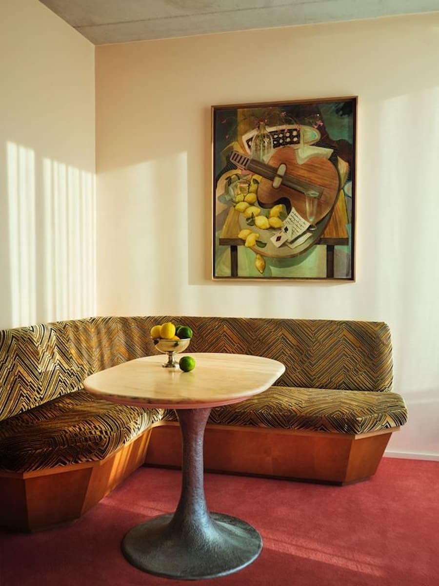 Curved lounge seating and vintage artwork inside a Bus Palladium Hotel Paris suite