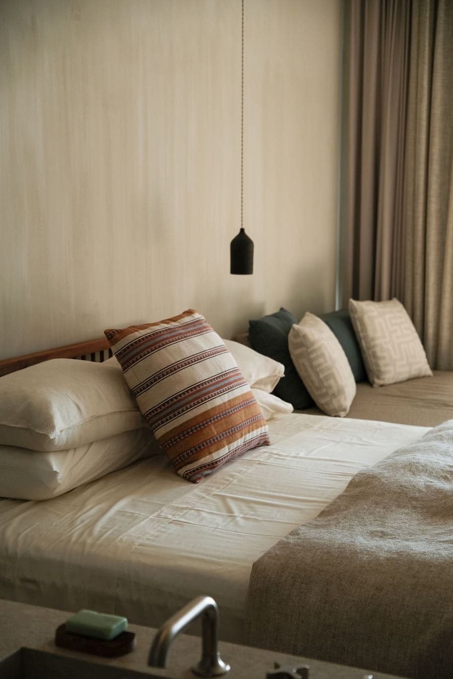 Minimal bedroom with integrated bathroom and panoramic sea views framed by floor-to-ceiling glazing