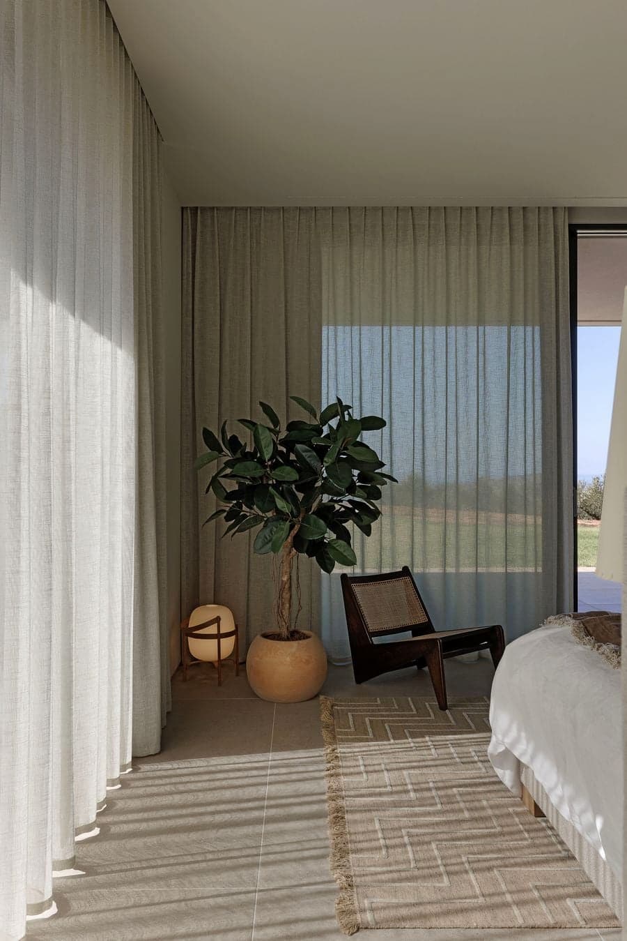 Bedroom corner with sheer linen curtains, lounge chair and soft natural daylight