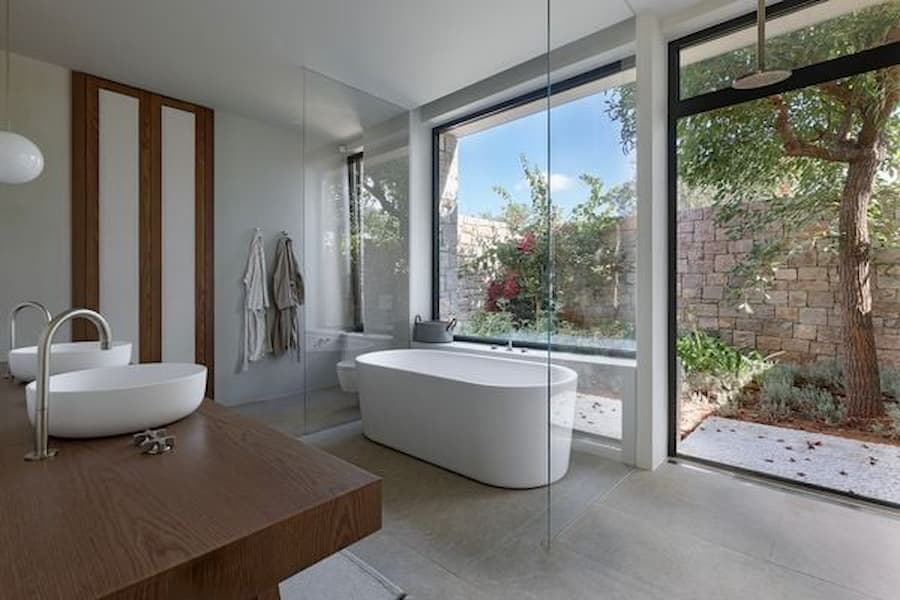 Minimal bathroom with freestanding bathtub opening onto a private garden courtyard