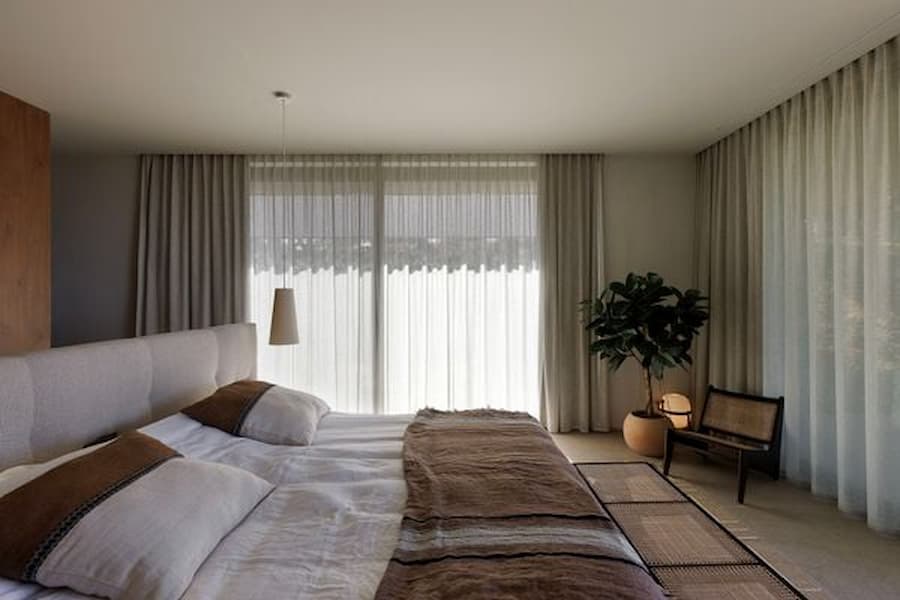 Guest bedroom with linen curtains, natural textures and tranquil garden views
