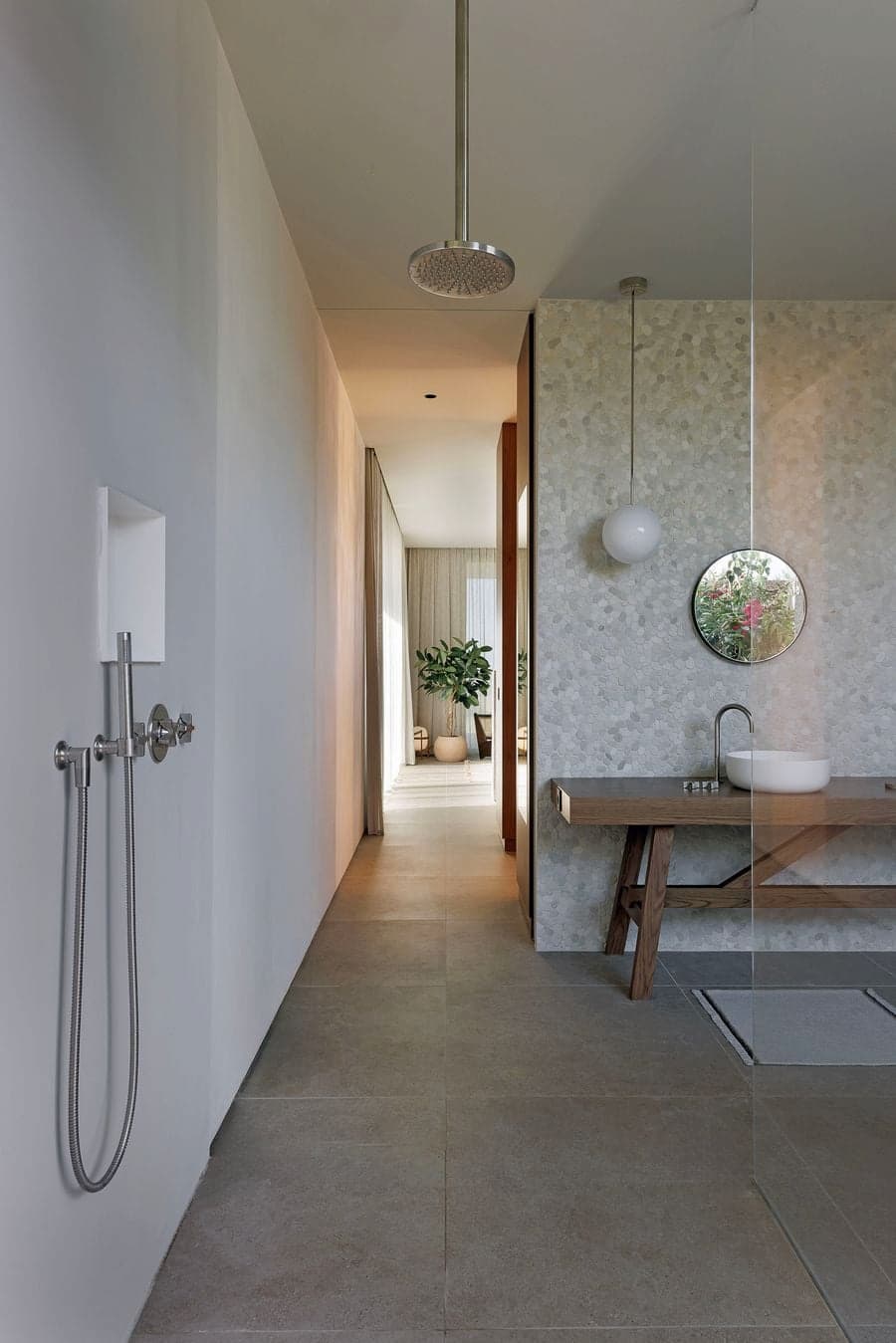 Walk-through bathroom finished with natural stone, timber vanity and minimalist fixtures