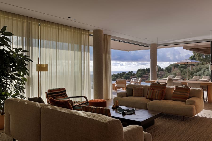 Living room opening seamlessly to the covered terrace with Mediterranean sea views