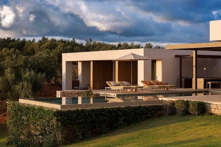 Minimal modern villa elevation with stone walls and expansive glazing at dusk