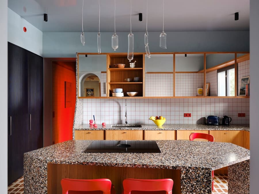 Custom terrazzo kitchen island paired with cherry wood cabinetry and hand-blown glass pendants in the Madrid villa.