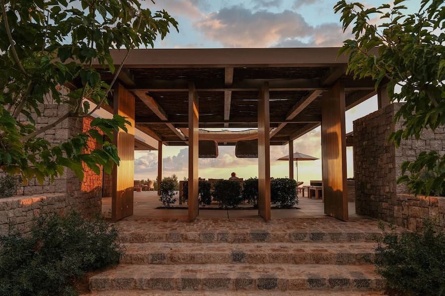 Outdoor lounge beside the infinity pool with panoramic Mediterranean sunset views