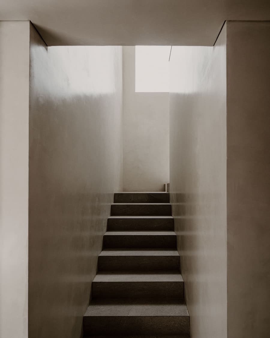 Minimal staircase illuminated by soft natural daylight from the overhead opening