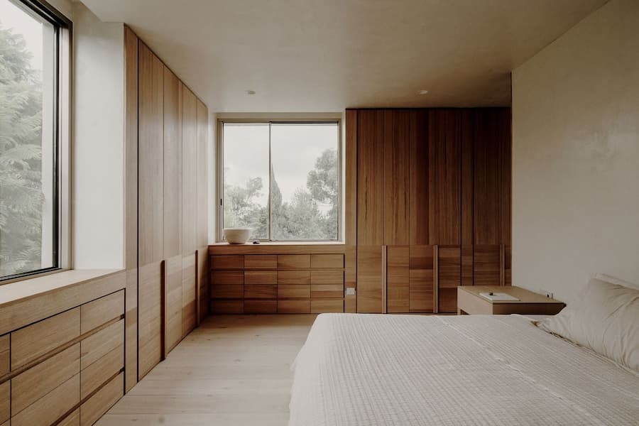 Warm timber bedroom combining built-in storage with soft natural materials
