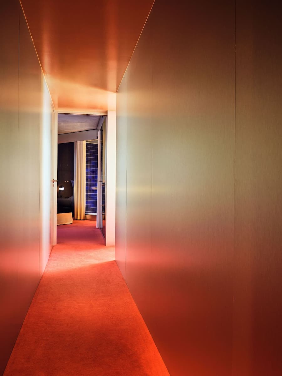 Warmly lit corridor connecting guest rooms inside Bus Palladium Hotel Paris