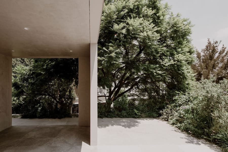 Covered terrace extending into a mature garden shaded by large trees