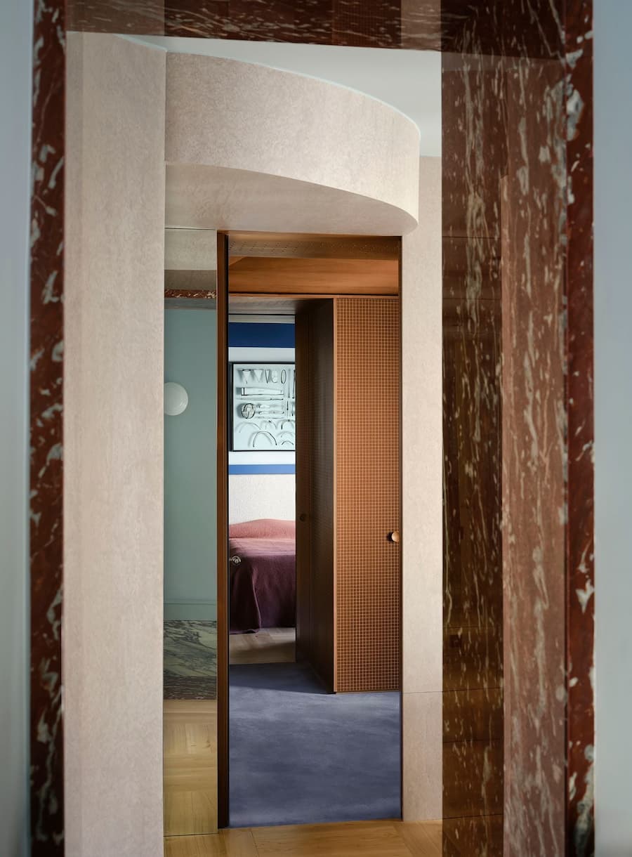 Curved passage leads toward the dressing room with custom cabinetry and warm material contrasts.