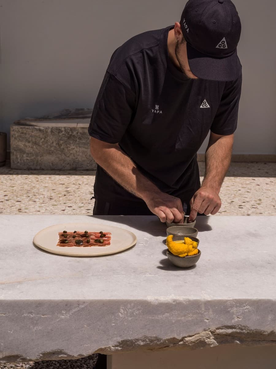 Chef plating a Mediterranean dish on a handcrafted marble table at YAPA Antiparos, Greece