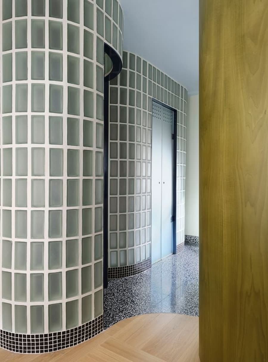 Curved glass block corridor introduces diffused daylight and sculptural circulation through the Madrid residence.