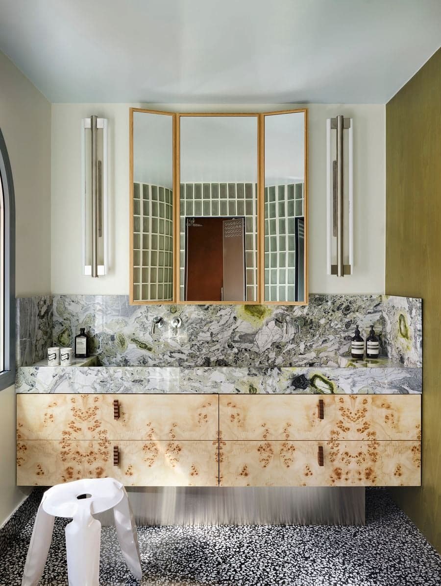 Custom marble bathroom vanity paired with burl wood cabinetry and mirrored storage in the renovated Madrid villa.