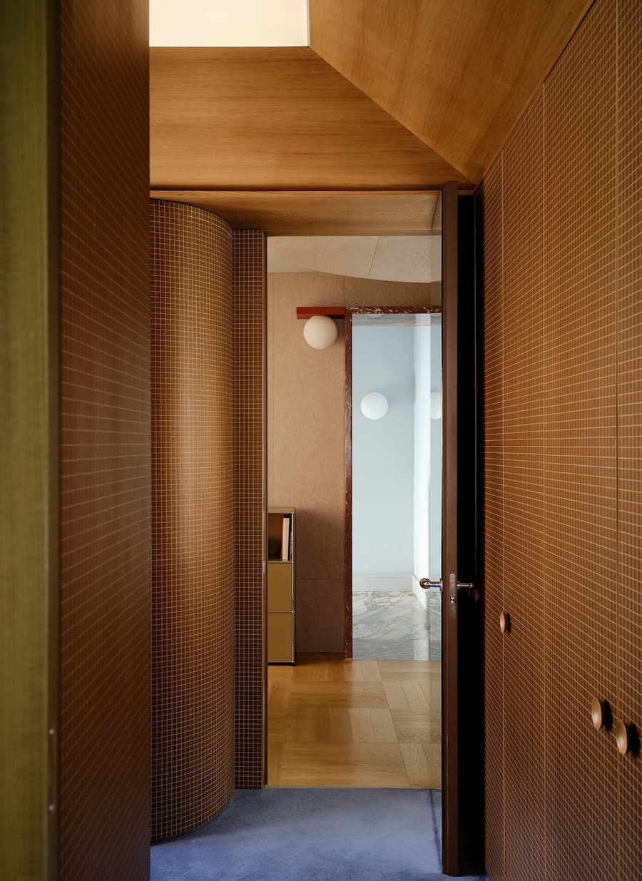 Natural light from a skylight highlights the curved tiled corridor and warm timber ceiling.