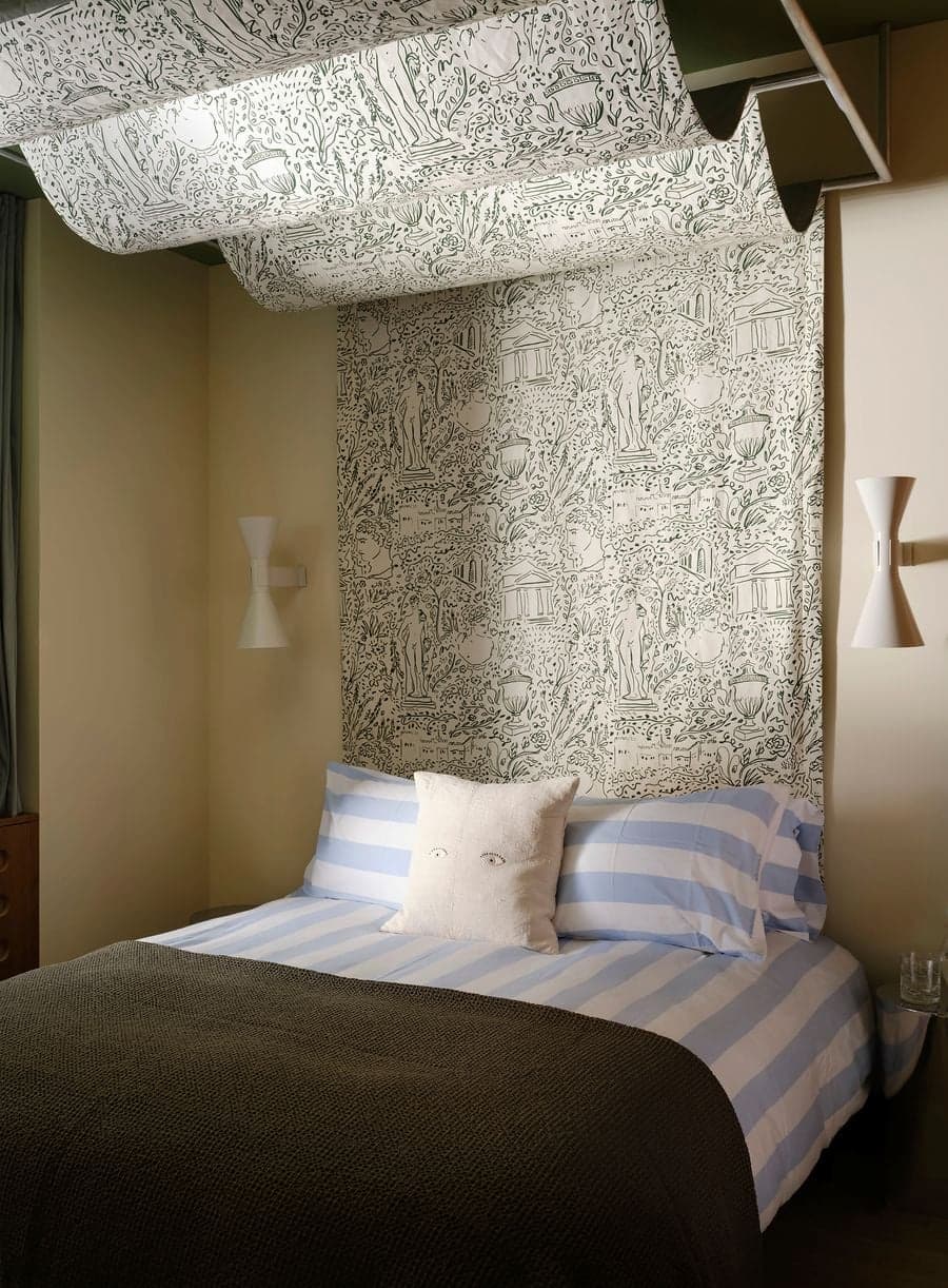 Guest bedroom featuring illustrated wall covering, layered textiles and soft ambient lighting.