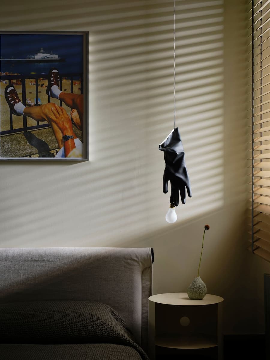 Bedroom detail with sculptural pendant light, filtered sunlight and contemporary artwork.