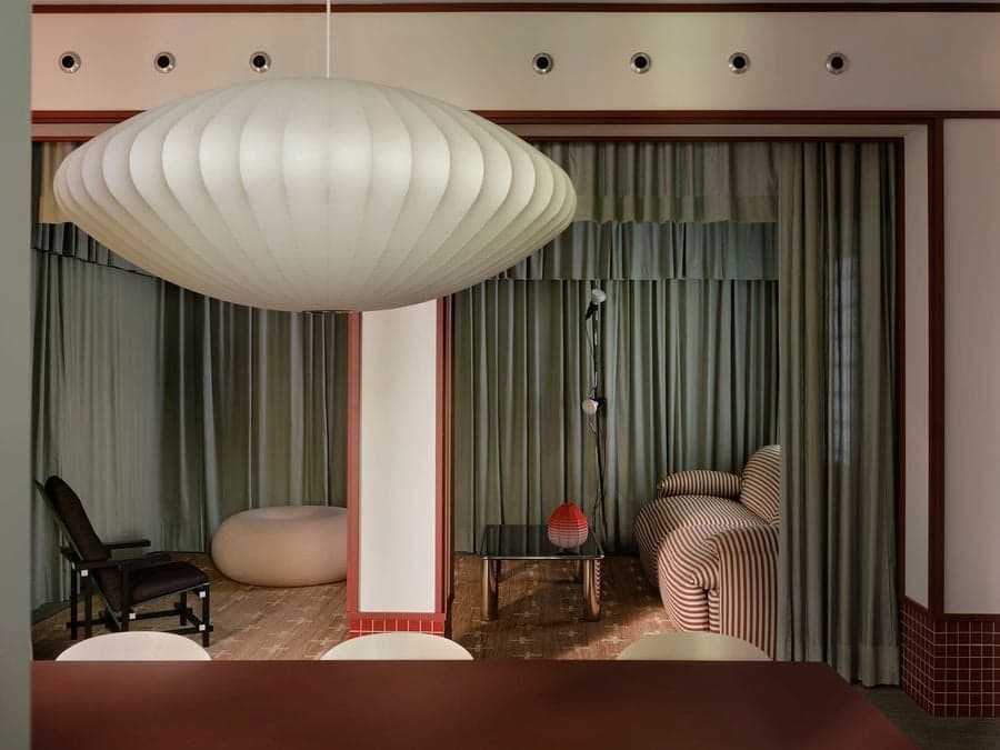 Open-plan living room framed by layered curtains, sculptural lighting and contemporary furnishings.
