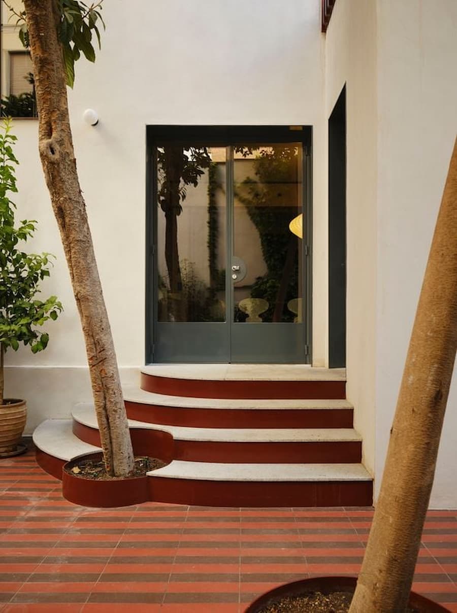 Curved courtyard entrance with terracotta steps and garden creates a welcoming transition into the residence.