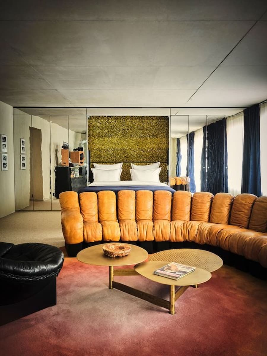 Spacious suite combining bedroom and lounge with mirrored walls in Bus Palladium Hotel Paris