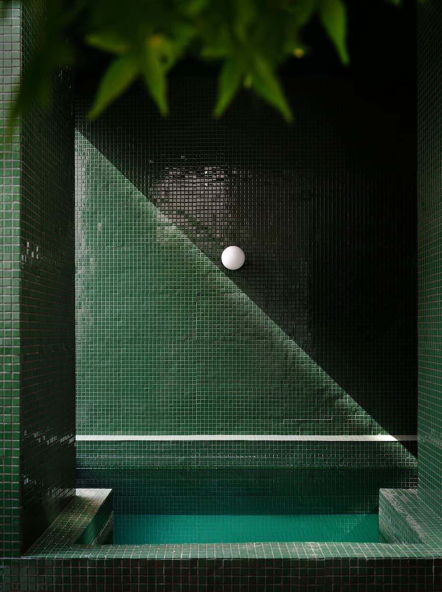 Green mosaic plunge pool creates a secluded outdoor retreat with soft light and geometric composition.