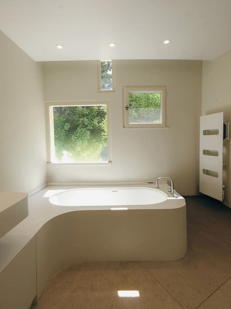 Minimal sculptural bathroom illuminated by natural light inside Villa Bank