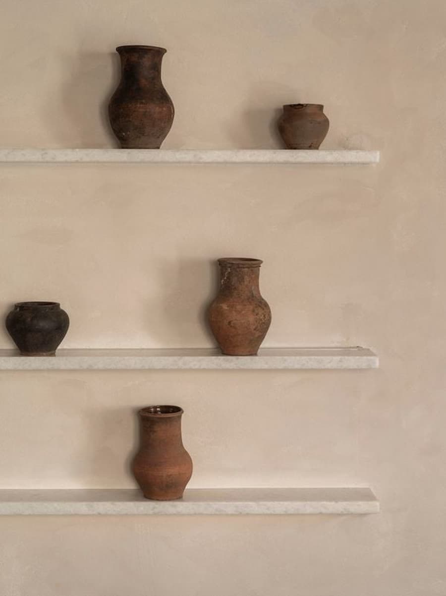 Traditional ceramic vessels displayed on marble shelves inside YAPA Antiparos, Greece