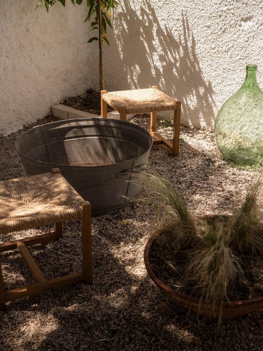 Rustic courtyard details with woven stools, recycled glass and Mediterranean planting at YAPA Antiparos, Greece