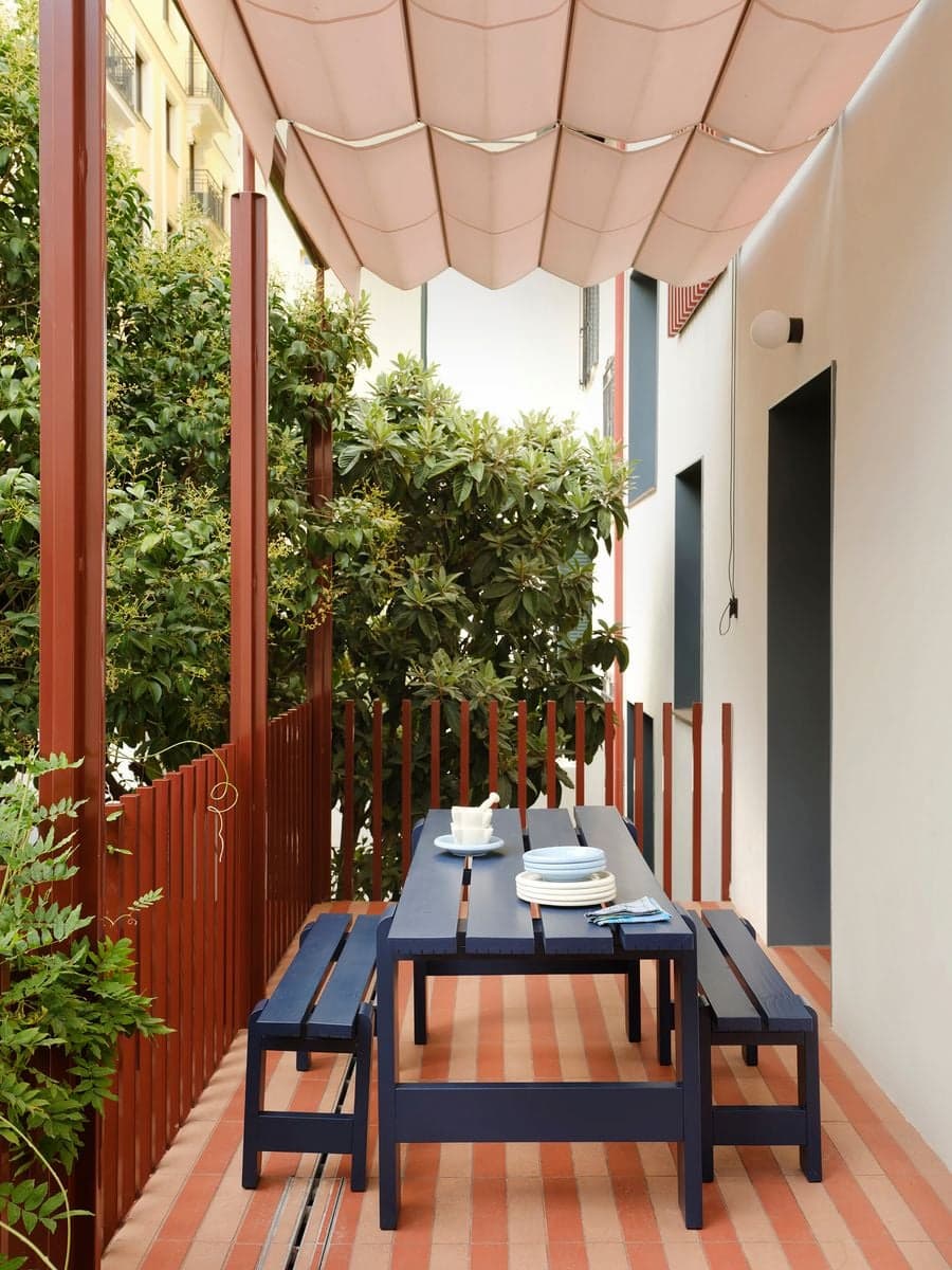Covered outdoor terrace with custom dining furniture, retractable canopy and landscaped garden setting.