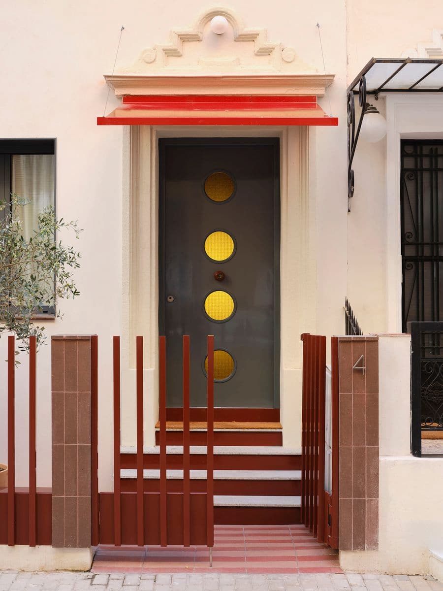 Renovated residential entrance with sculptural front door, terracotta steps and contemporary metal canopy.