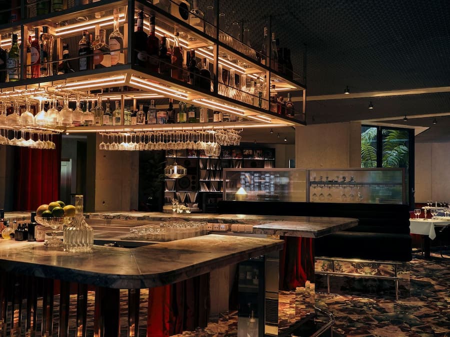 Floating liquor shelves frame the marble cocktail bar inside Bus Palladium Hotel Paris