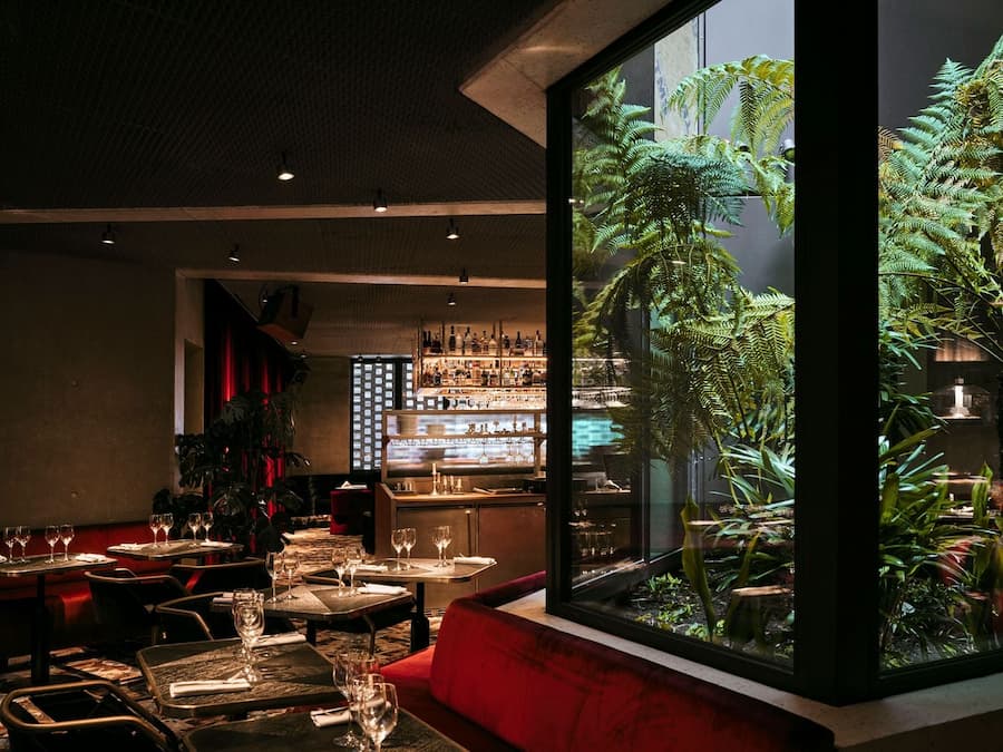 Dining room overlooking a lush interior courtyard filled with tropical greenery