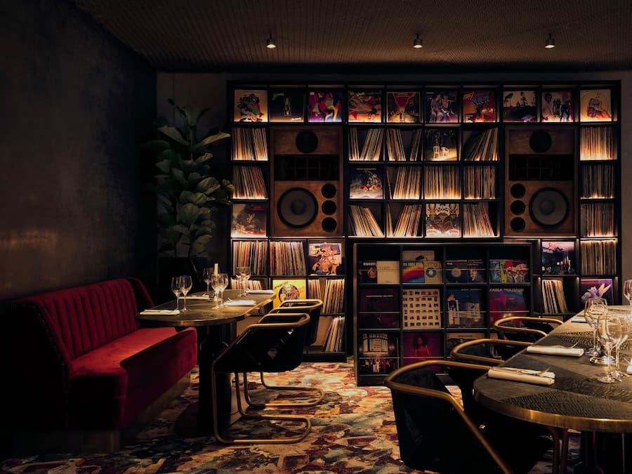 Restaurant interior featuring floor-to-ceiling vinyl records and custom audio speakers