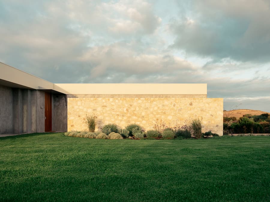 Limestone entry wall blending architecture and coastal landscape at Wildcoast Residence.
