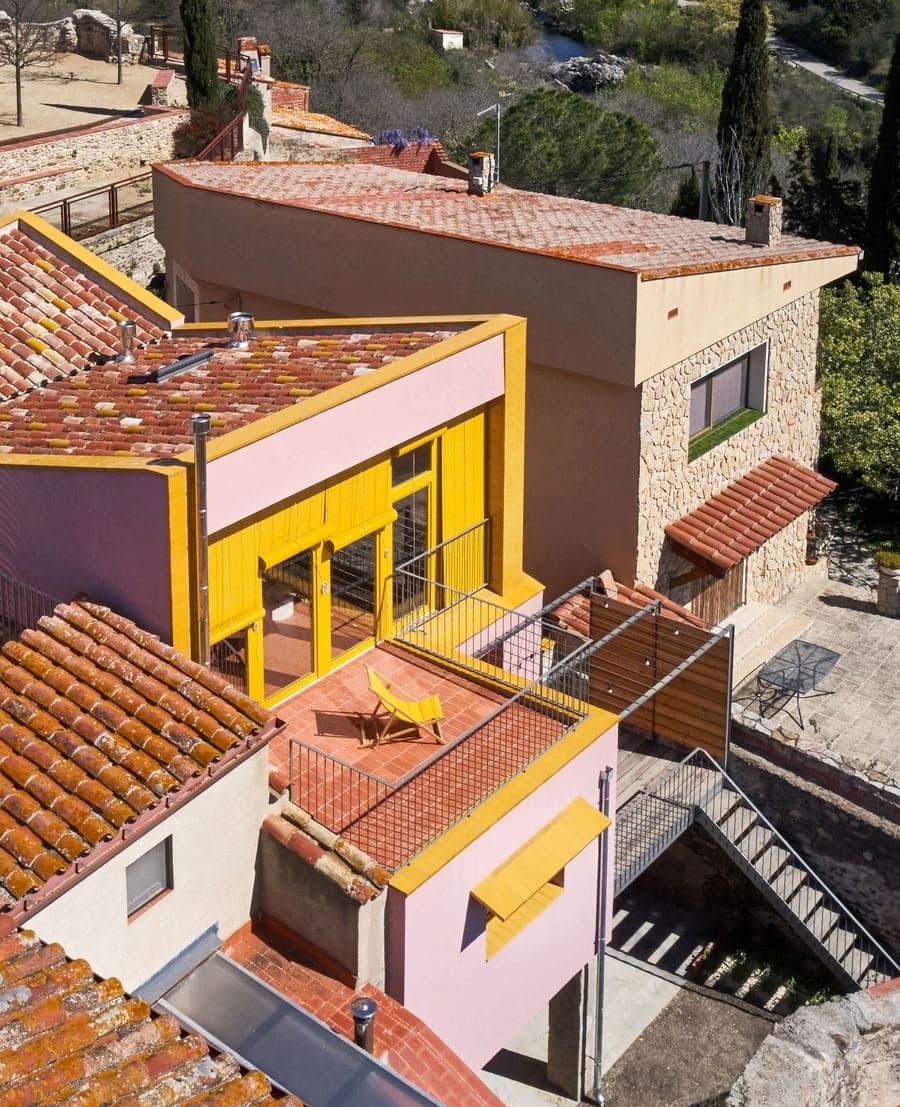 Pink exterior and yellow facade overlooking the village at Ca la Carolina by Lacol and Altura Arquitectes.