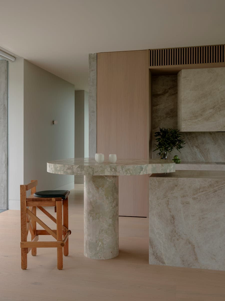 Natural stone kitchen island with timber cabinetry inside Wildcoast Residence.