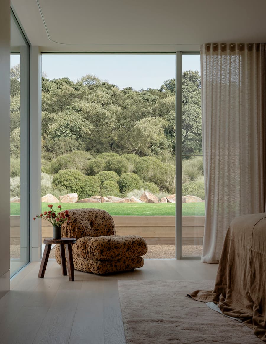 Bedroom overlooking native landscape through full-height glazing at Wildcoast Residence.