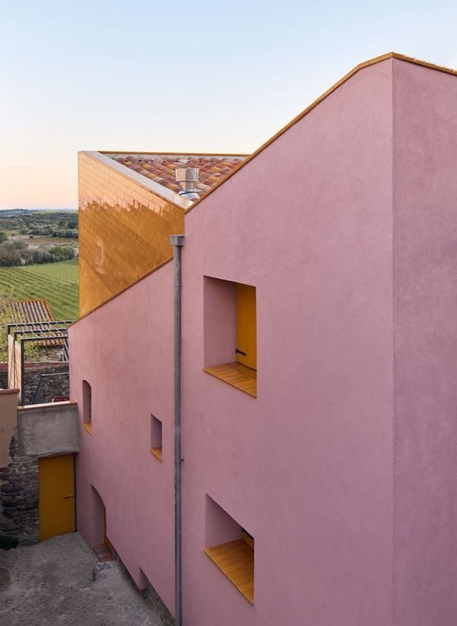 Pink plastered exterior wall and ceramic-clad roof volume at Ca la Carolina.