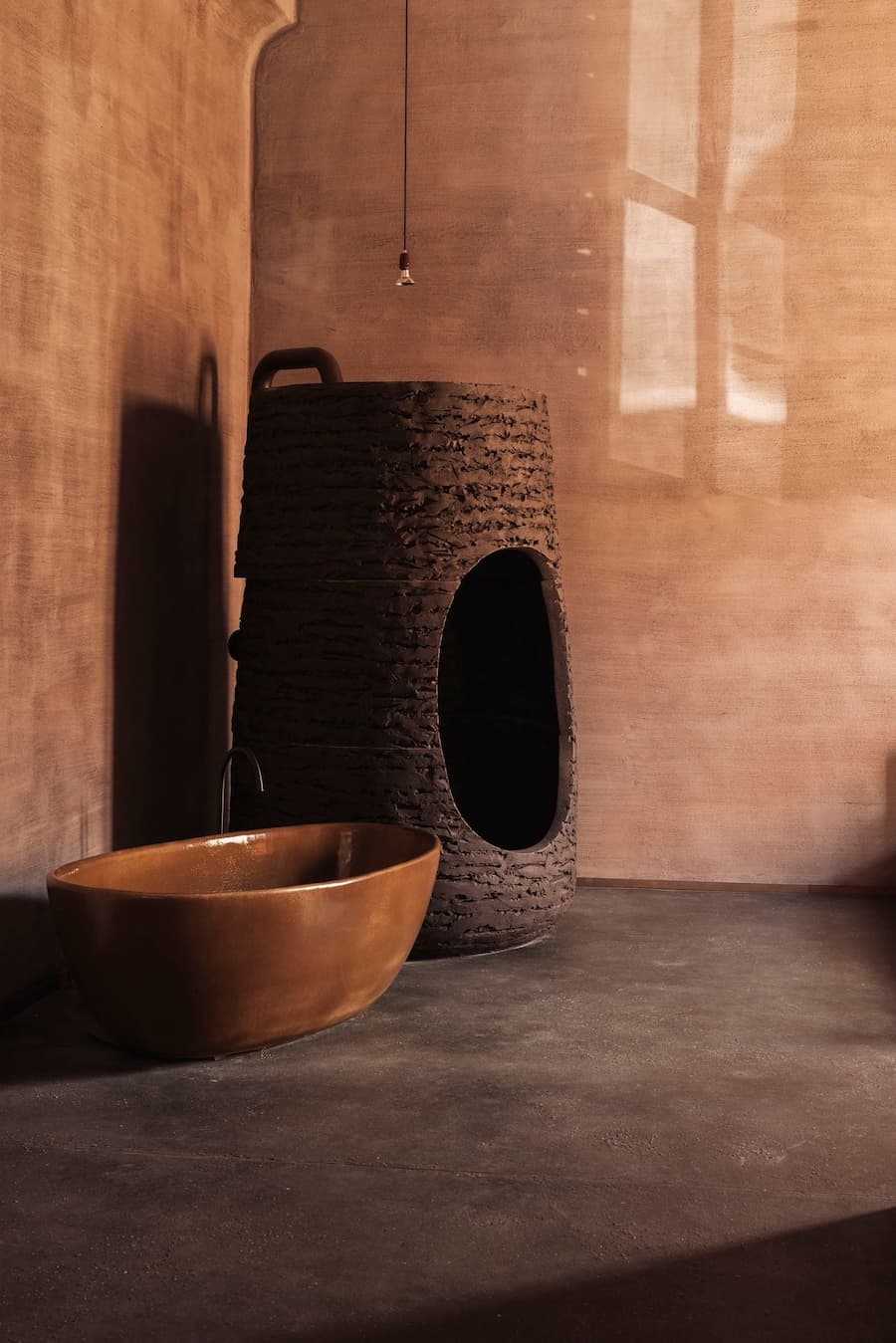 A sculptural clay bathroom features a freestanding basin and an enclosed textured shower cabin
