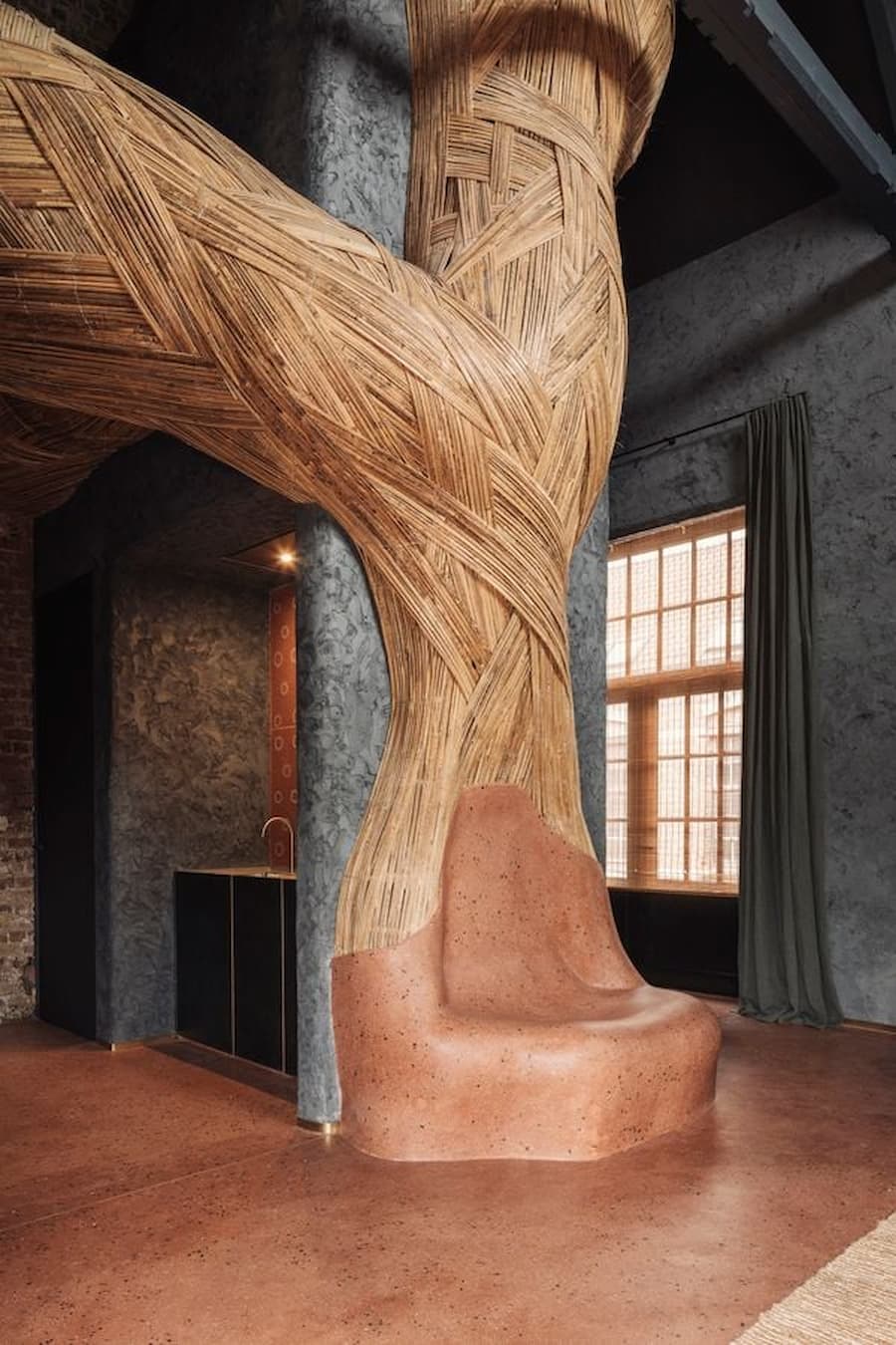 Curved bamboo weaving meets a handmade clay seat beside a timber-framed window