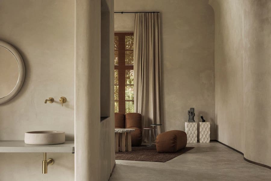 A minimalist washbasin opens toward a warm lounge through a softly curved plaster interior